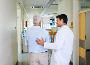 handsome young doctor walking with his senior patient down the hall