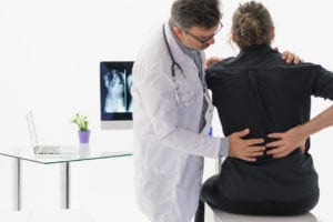 doctor checking a male patient's back forDegenerative Scoliosis