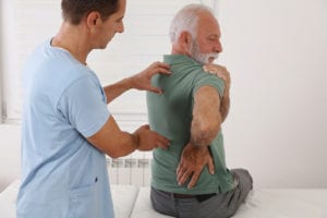 Senior man with back pain. Spine physical therapist and paient.