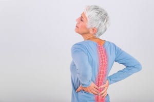 elderly woman experiencing back pain with spine illustration highlighted in red