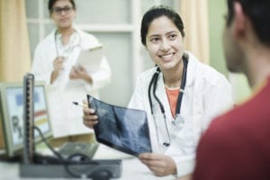Female orthopedics doctor holding x-ray image and talking to patient.