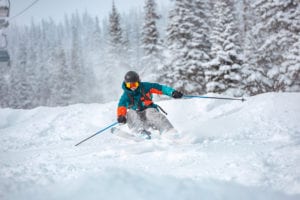 skier rides over off-piste slope in snow capped forest