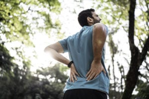 Sportsman feeling backache at a park while jogging