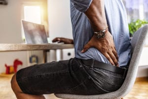 young businessman suffering from a backache while working at his desk in his office
