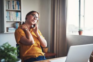 Cropped shot of an attractive young businesswoman sitting alone in her home office and feeling stressed while using her cellphone