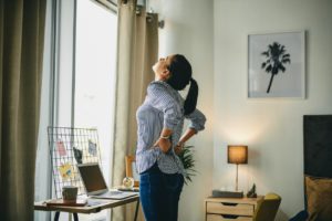 Rearview shot of a young woman suffering with back pain while working from home
