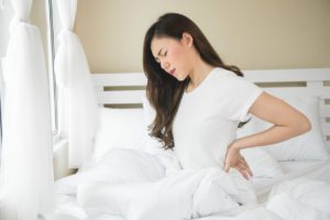 Woman getting out of bed with back pain