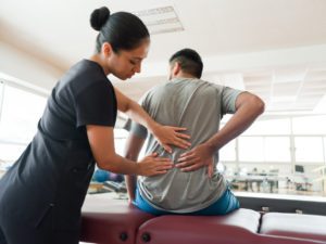 Physical therapist examining a male patient's back pain