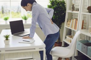 Woman standing at her desk with lower back pain