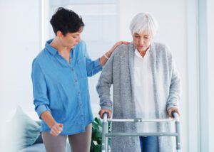 young woman helping her senior mother walk with her walker