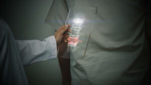 Futuristic concept of a doctor using an advance transparent x-ray pad scanning a patient's backbone looking for a sign of spinal disc herniation