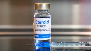 Bottle of Steroid injection with a syringe on black table