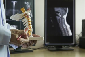 A neurosurgeon pointing at cervical spine model