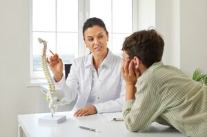 A curious boy listens attentively to an orthopedic spine surgeon discussing scoliosis of the spine.