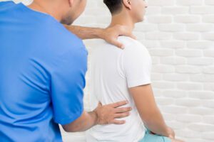 A male doctor is providing therapy for a patient with lower back pain at a clinic.